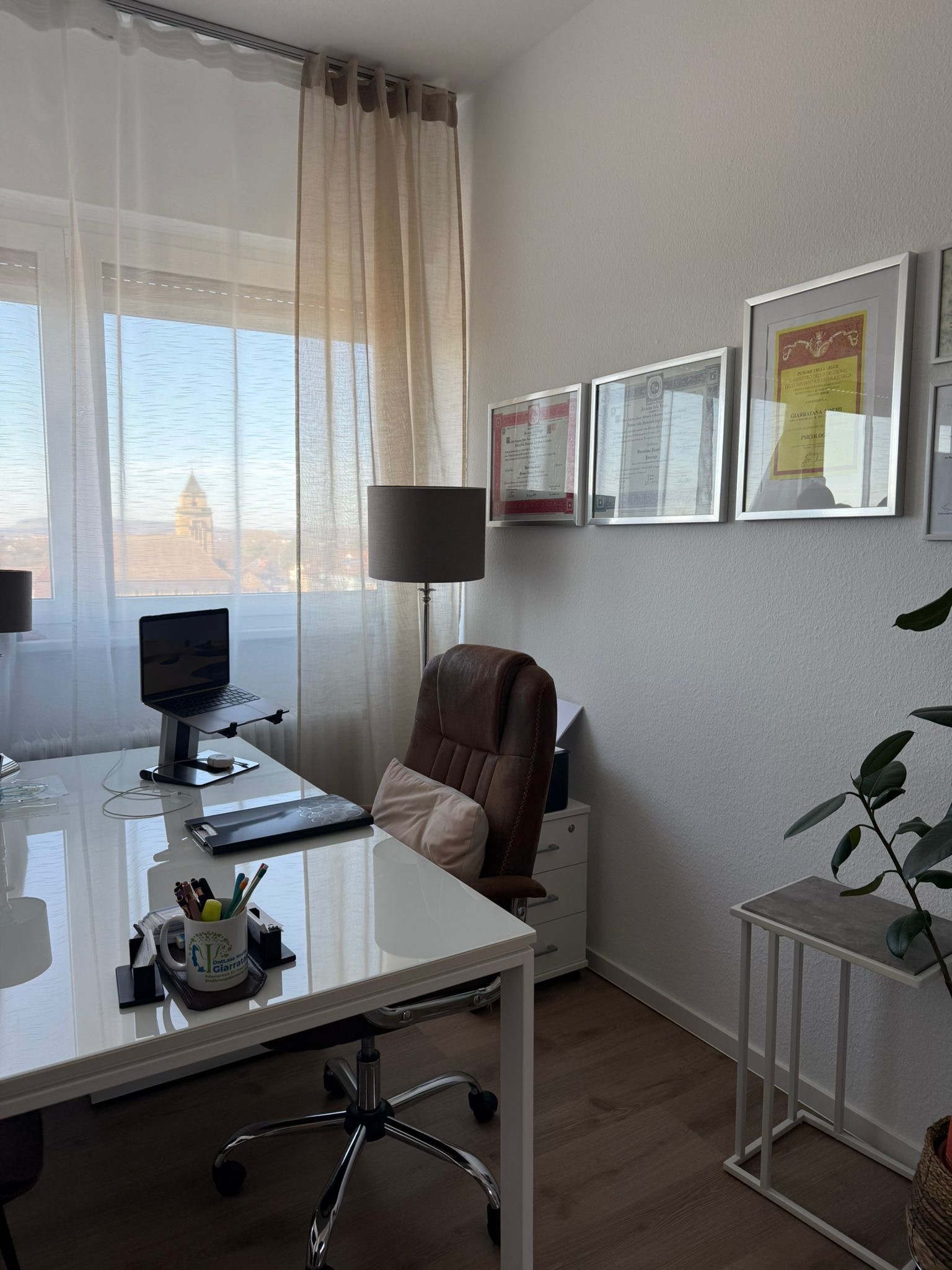 Angolo dello studio con luce naturale e diplomi